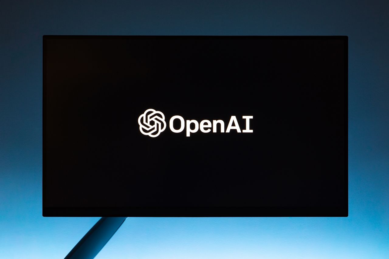 contact-img Minimalist display of OpenAI logo on a screen, set against a gradient blue background.